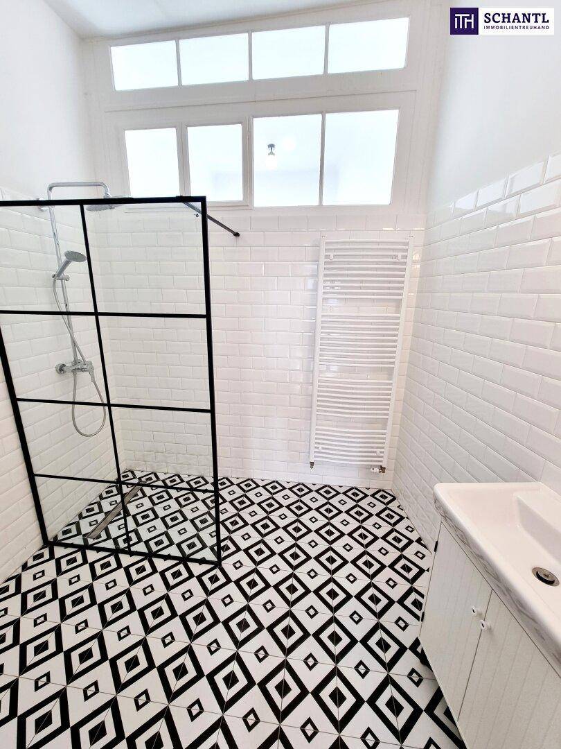 Helles Badezimmer mit begehbarer Dusche, Heizkörper und auffälligen schwarz-weiß gemusterten Bodenfliesen.