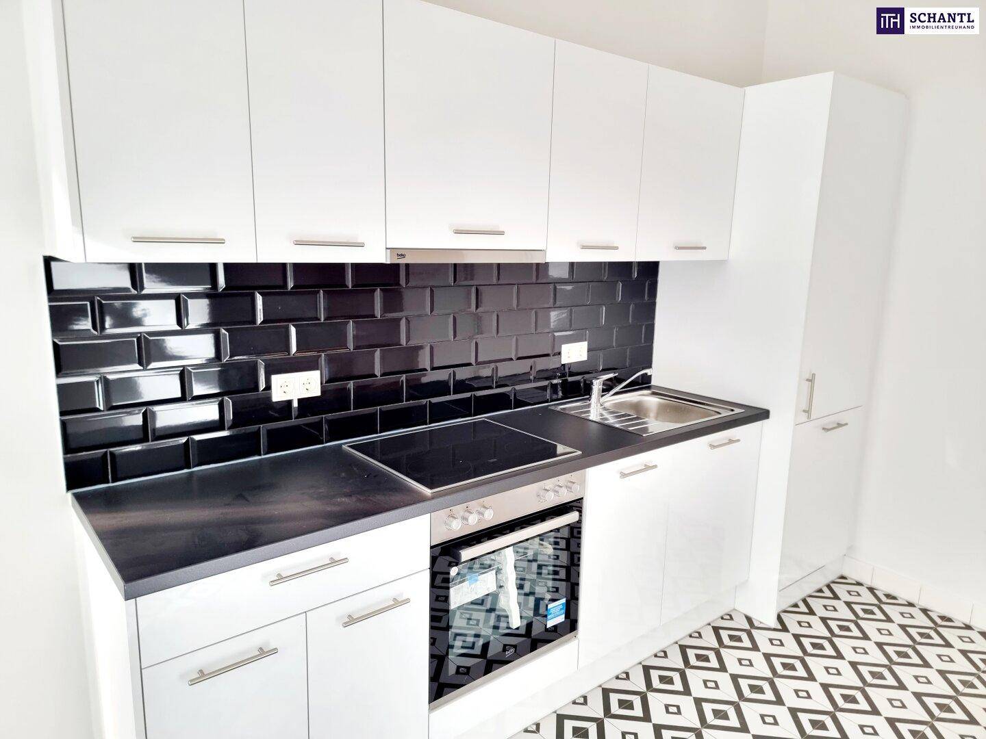 Moderne Einbauküche mit weißen Schränken, schwarzer Arbeitsplatte und glänzenden schwarzen Fliesen.