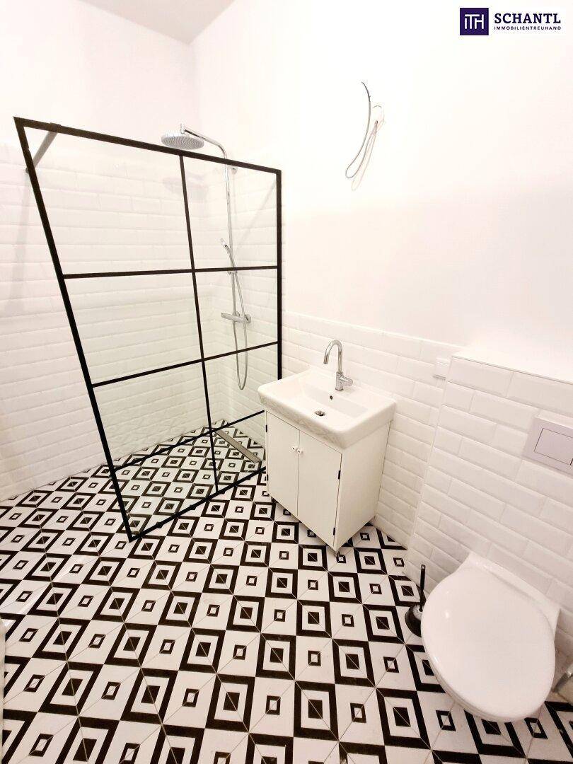 Modernes Badezimmer mit Duschkabine, Waschbecken und WC, auf markantem schwarz-weißem Fliesenboden.
