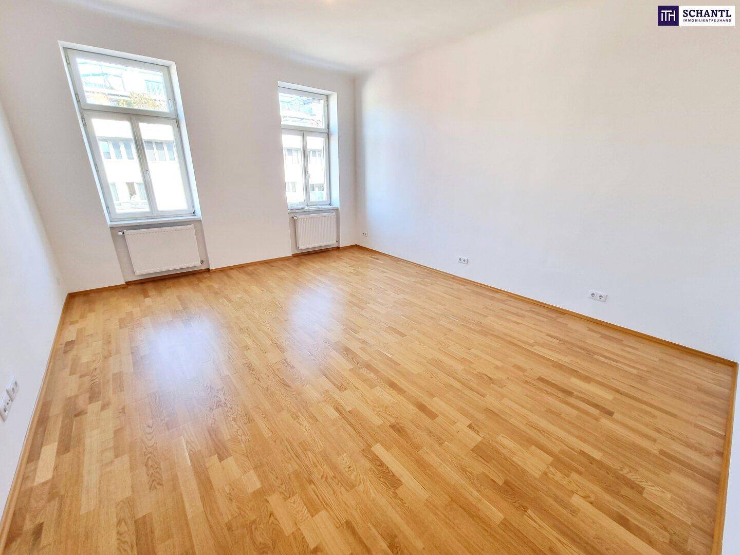 Heller Raum mit Holzparkett und großen Fenstern, die eine angenehme Wohnatmosphäre schaffen.