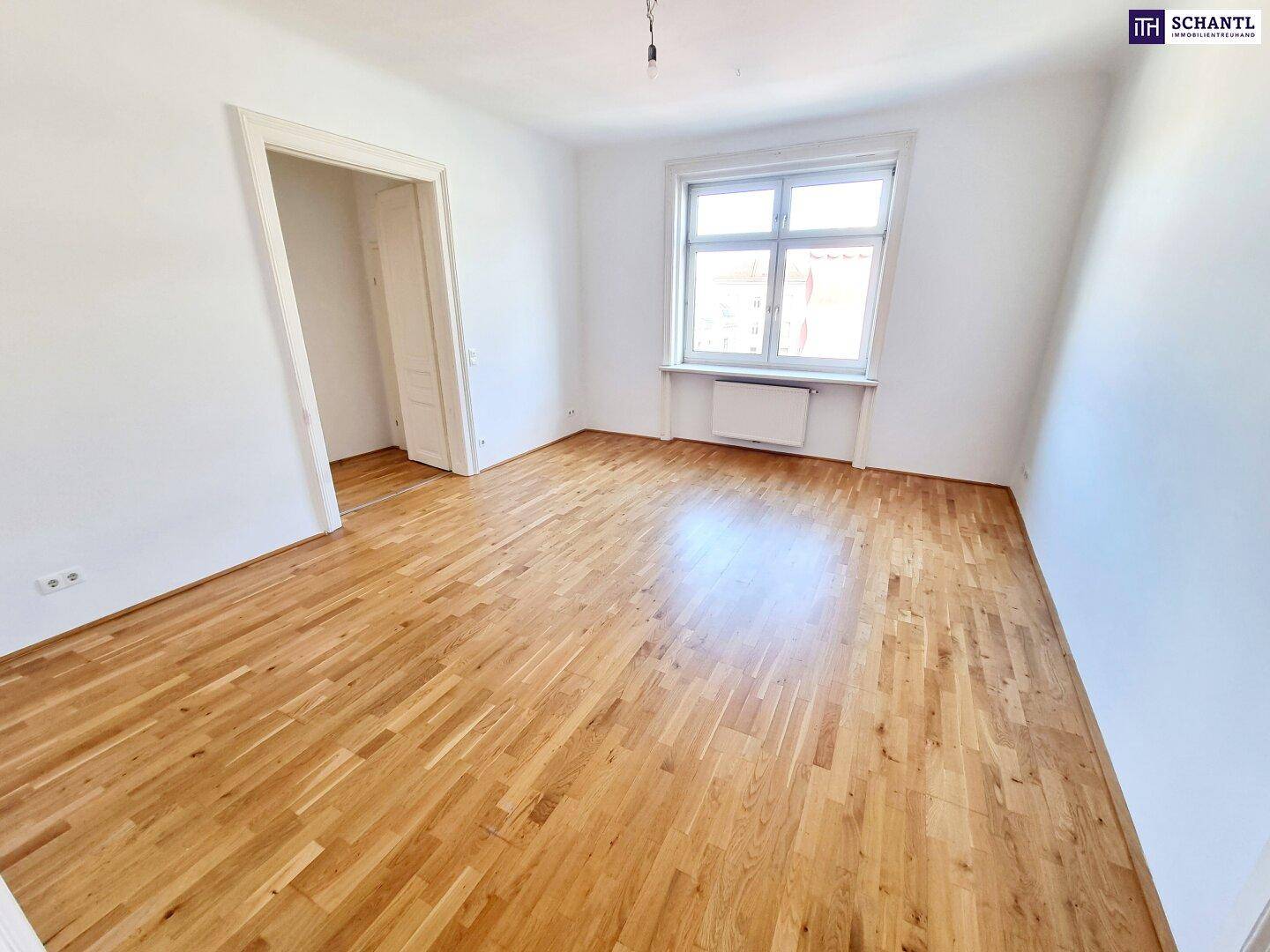 Geräumiges Zimmer mit Parkettboden und großem Fenster, ideal für Schlaf- oder Arbeitsbereich.
