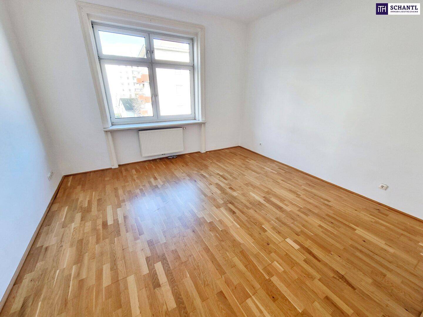 Helles Zimmer mit Parkettboden und Fenster, bietet eine angenehme Wohnatmosphäre.