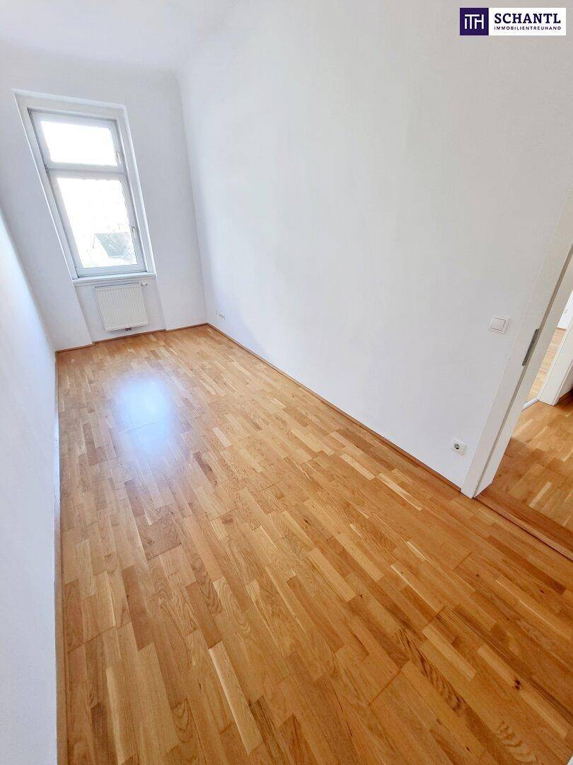 Langes, schmales Zimmer mit Parkettboden und Fenster, vielseitig nutzbar.
