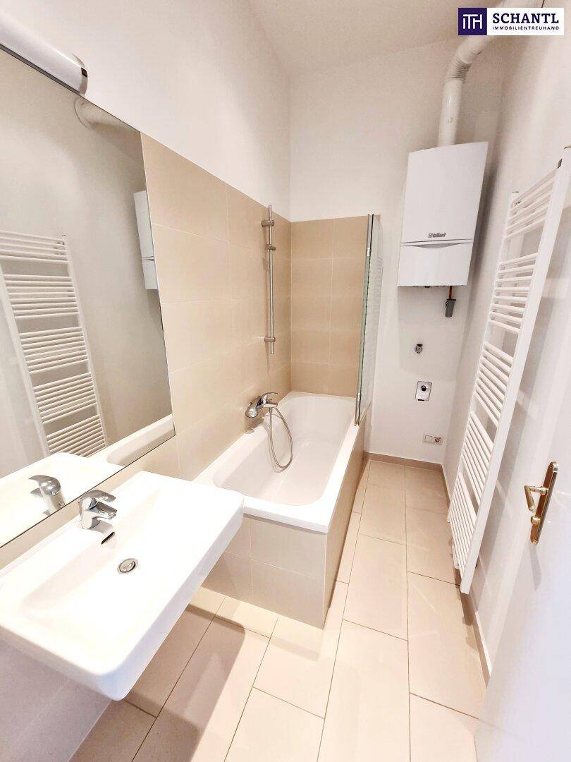 Modernes Badezimmer mit Badewanne, Einzelwaschbecken und beheiztem Handtuchhalter.