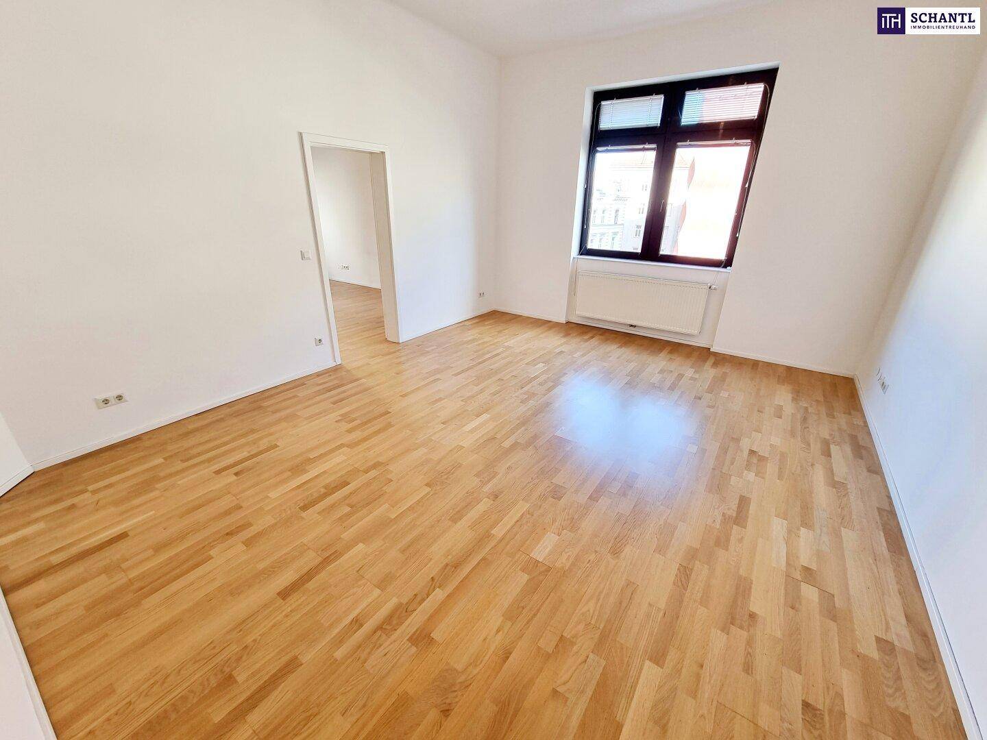 Geräumiger Raum mit Holzparkett und viel Tageslicht durch das große Fenster.
