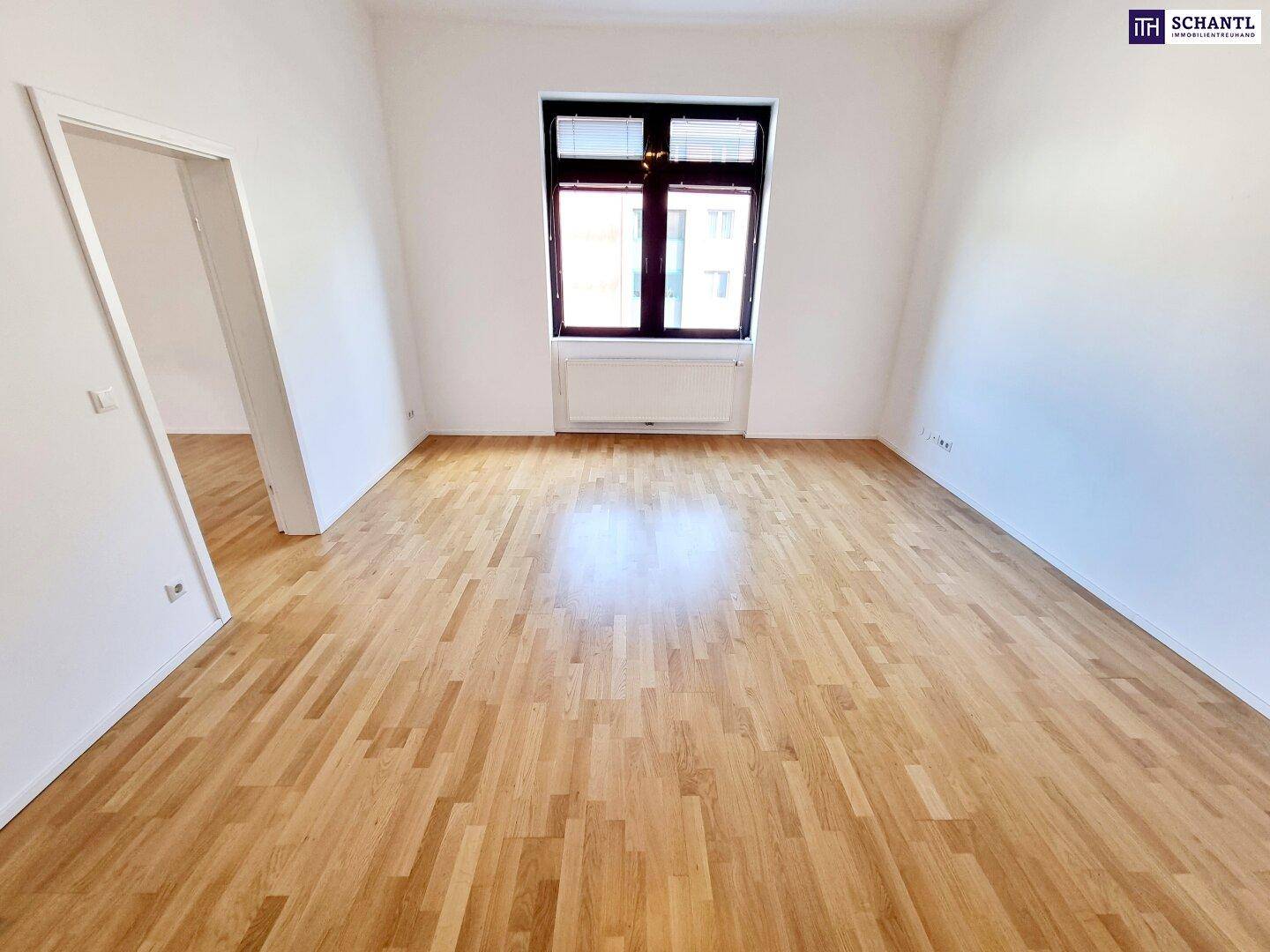 Großes Zimmer mit Parkettboden und Fenster, das sich gut als Wohn- oder Schlafzimmer eignet.