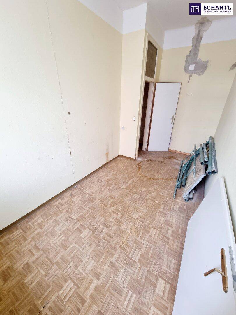 Leeres Zimmer mit hellem Holzboden und schlichten Wänden, das auf eine Neugestaltung wartet.