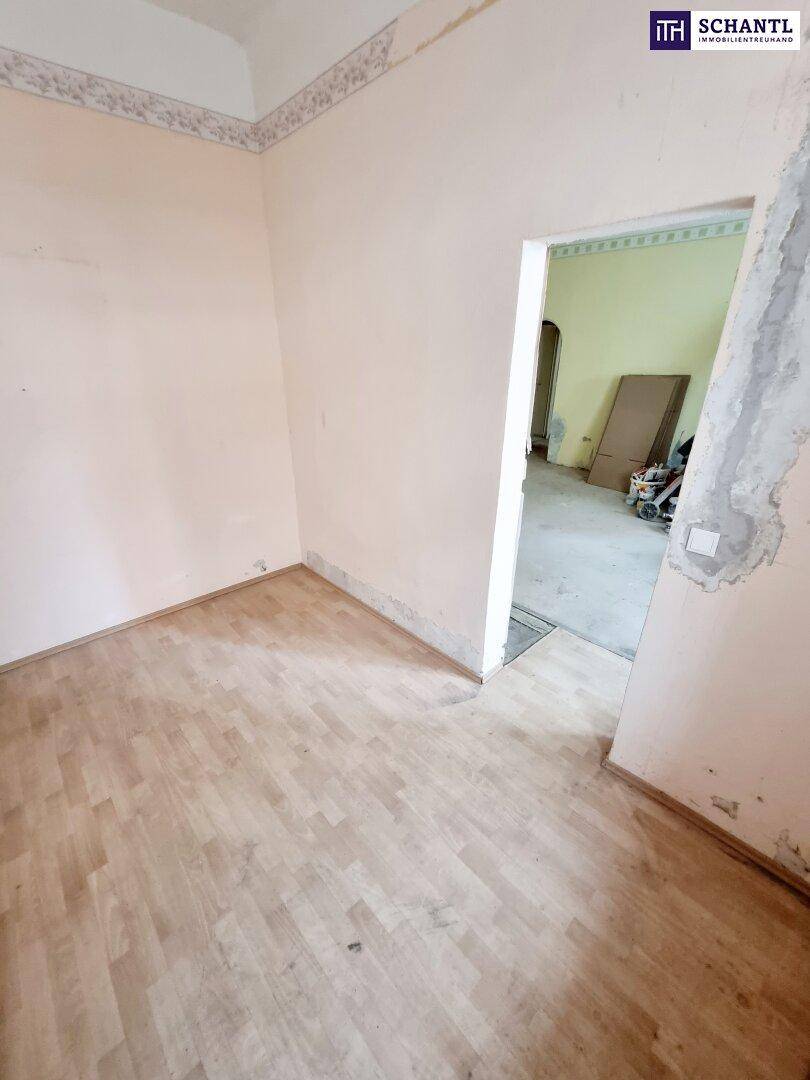 Leeres Zimmer mit hellem Holzboden und schlichten Wänden, das auf eine Neugestaltung wartet.