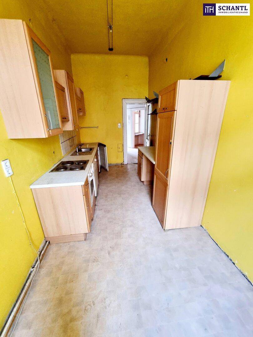 Funktionale Küche mit gelben Wänden, Holzschränken und einfacher Ausstattung.