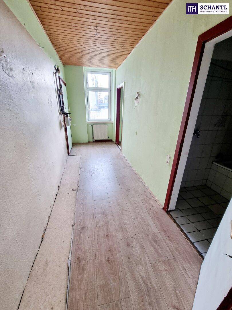 Langer Flur mit Laminatboden, Holzdecke und Zugang zu verschiedenen Räumen.