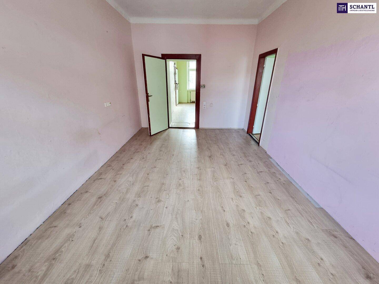 Geräumiger Raum mit Laminatboden und rosa gestrichenen Wänden, bereit für Renovierung.
