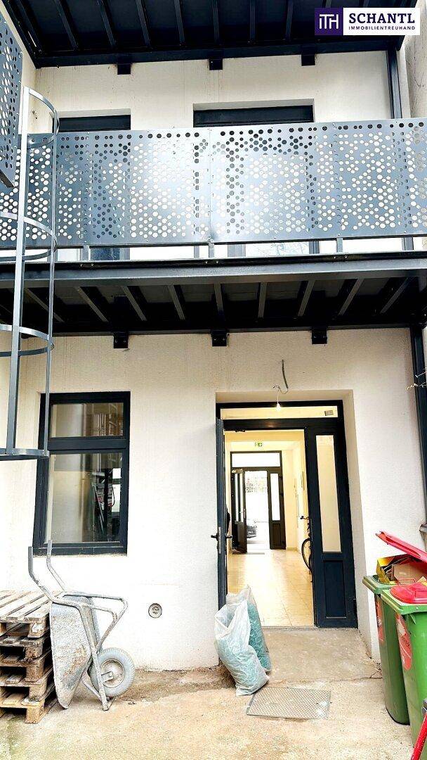 Hintereingangsbereich mit modernem Metallbalkon und Zugang zum Gebäude.