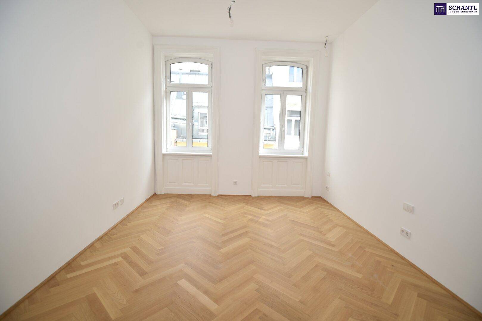 Heller Raum mit zwei hohen Fenstern und klassischem Fischgrätparkett, ideal für Wohn- oder Schlafbereich.