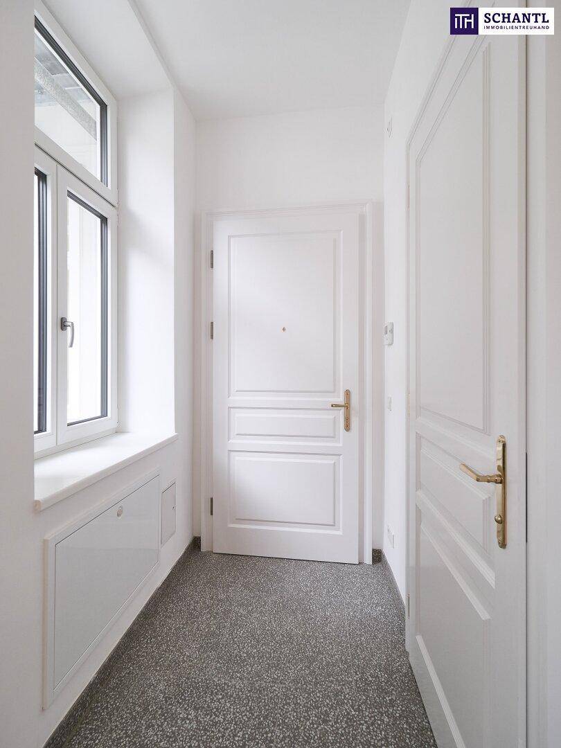 Heller Eingangsbereich mit Fenster, Terrazzoboden und weißer Tür.