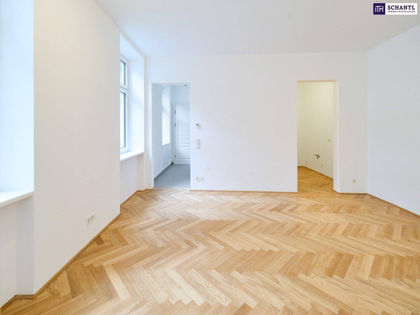 Geräumiges, helles Zimmer mit Fischgrätparkett und zwei großen Fenstern.