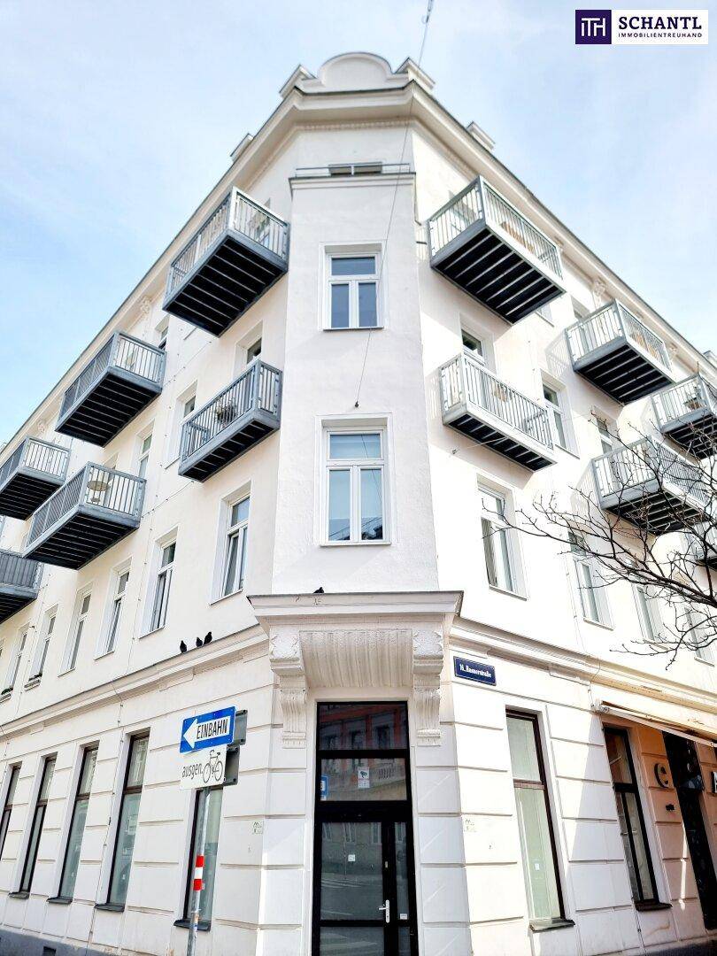Eckansicht eines weißen Mehrfamilienhauses mit zahlreichen kleinen Balkonen und klassischer Fassadengestaltung.