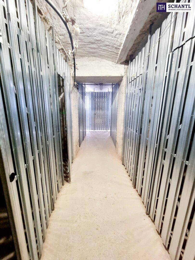 Langer Kellergang mit neuen Metallabtrennungen für individuelle Abstellräume.
