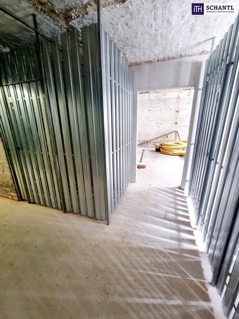 Kellerbereich mit neuen Metallabtrennungen und Blick in einen weiteren Rohbau-Raum.
