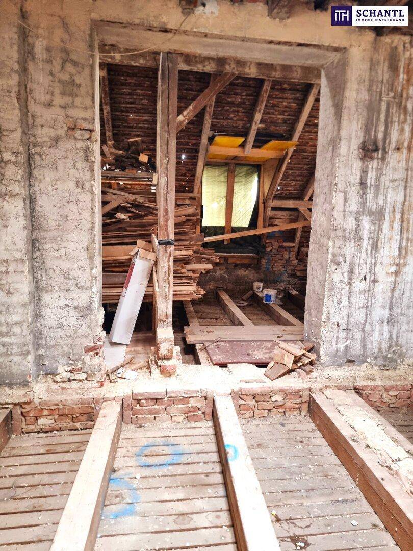 Innenraum im Rohbau mit Blick auf den Dachboden und sichtbaren Holzstrukturen.