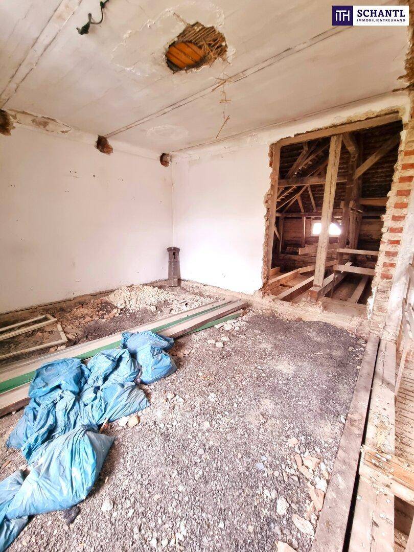 Rohbauzimmer mit Schutt auf dem Boden und sichtbaren Mauerwerkselementen.