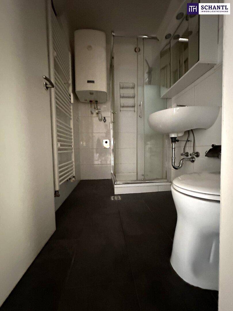 Kleines Badezimmer mit Dusche, WC, Waschbecken und beheiztem Handtuchhalter.
