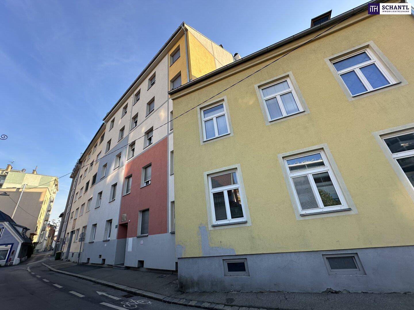 Mehrfamilienhaus mit farbiger Fassade an einer ruhigen Wohnstraße.