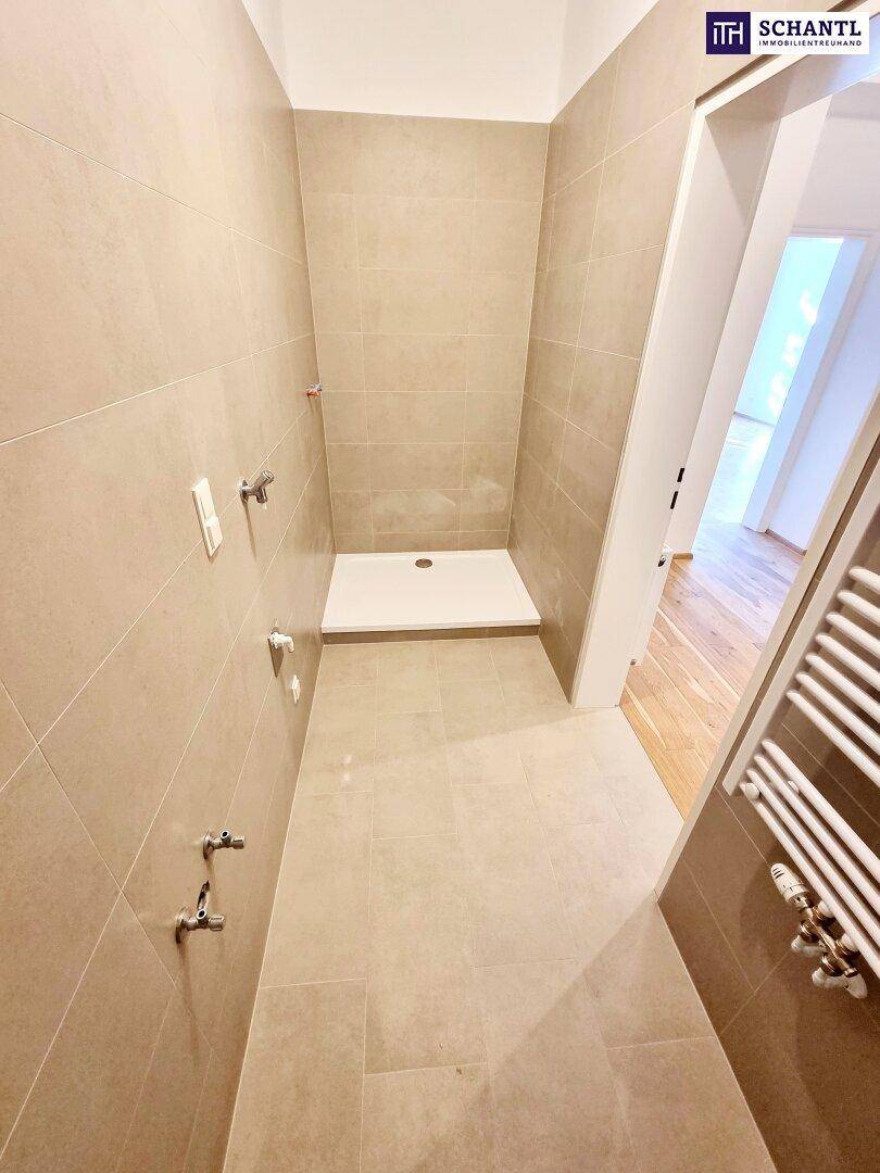Modernes Badezimmer im Bau mit beigefarbenen Fliesen, vorbereitet für eine begehbare Dusche und Heizkörper.