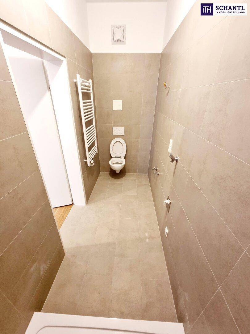 Badezimmer mit beigefarbenen Fliesen, wandhängendem WC und Heizkörper, bereit für die Installation des Waschbeckens.