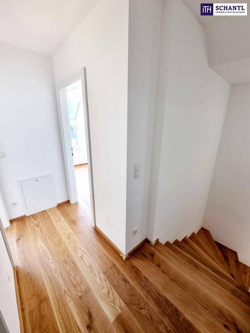 Heller Flur mit Holzboden und Zugang zu weiteren Räumen sowie einer modernen Holztreppe.