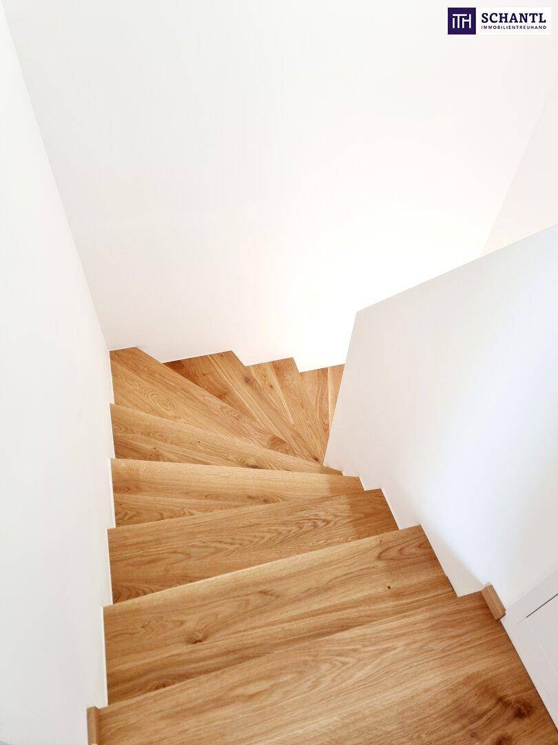 Elegante Holztreppe mit weißem Geländer, die verschiedene Ebenen des Hauses verbindet und modern gestaltet ist.
