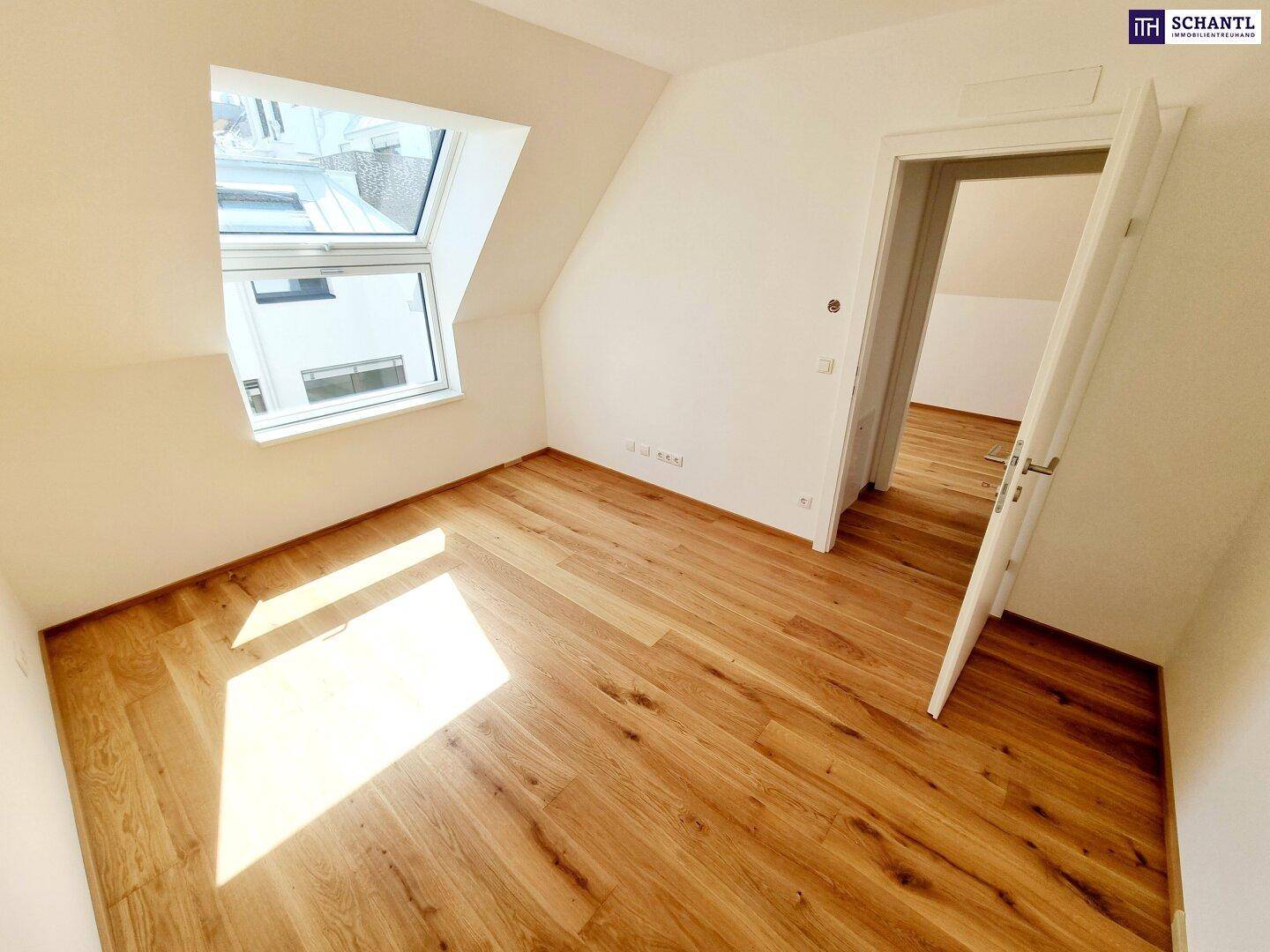Helles Schlafzimmer im Dachgeschoss mit Holzboden und großem Dachfenster, das viel Tageslicht hereinlässt.
