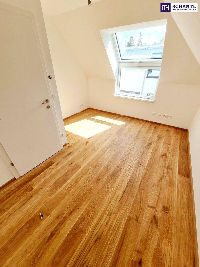 Lichtdurchflutetes Dachzimmer mit Holzboden und einem großen Fenster, das eine angenehme Wohnatmosphäre schafft.