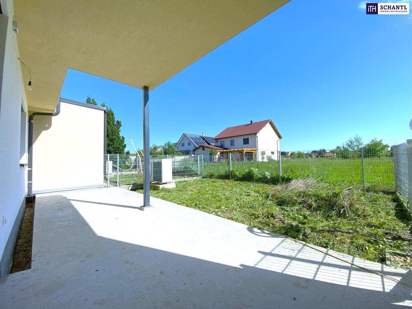 Überdachte Terrasse mit Betonboden und Blick auf die angrenzende Grünfläche.