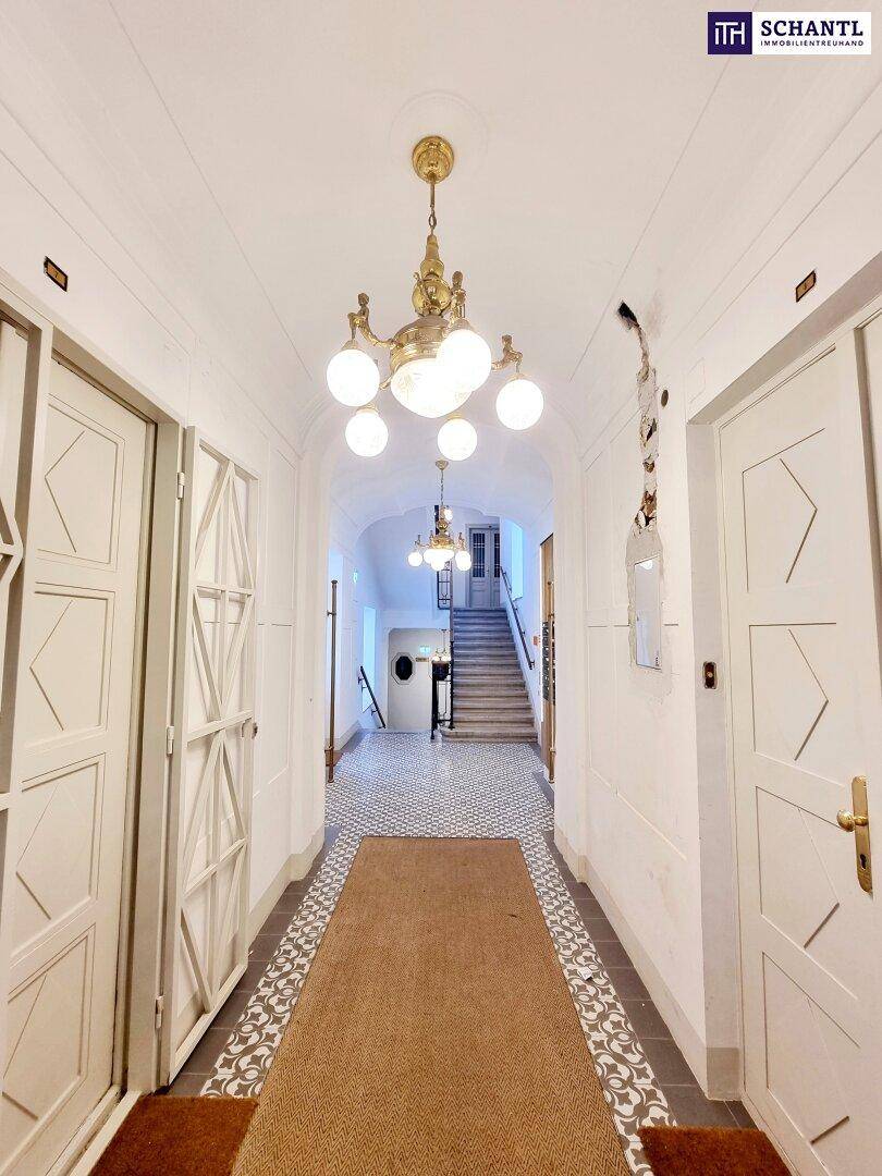 Langer Hausflur mit dekorativen Bodenfliesen, mehreren Türen und eleganter Deckenleuchte.