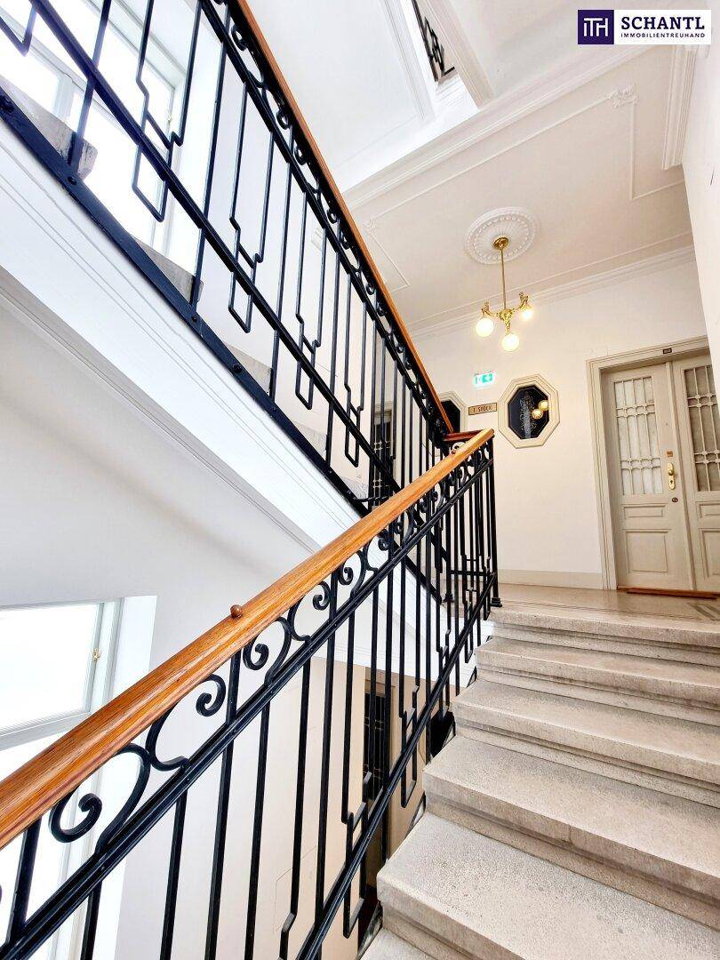 Elegantes Treppenhaus mit schmiedeeisernem Geländer, Holzhandlauf und Stuckdecke.