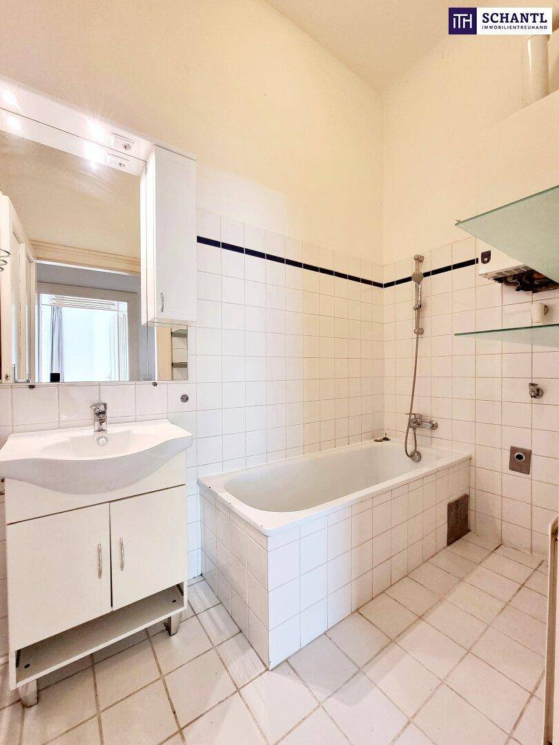 Badezimmer mit weißen Fliesen, Badewanne, Einzelwaschbecken und Spiegelschrank.
