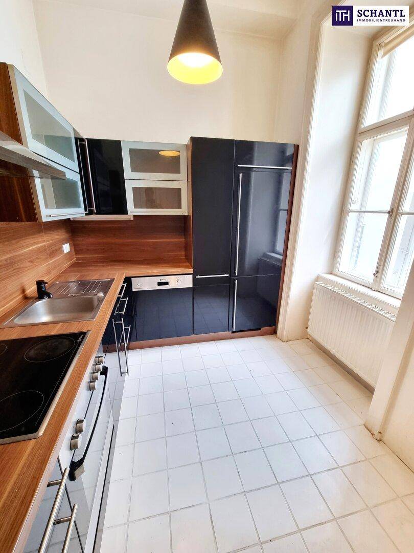 Moderne Küche mit schwarzen Schränken, Holzarbeitsplatten und weiß gefliestem Boden.