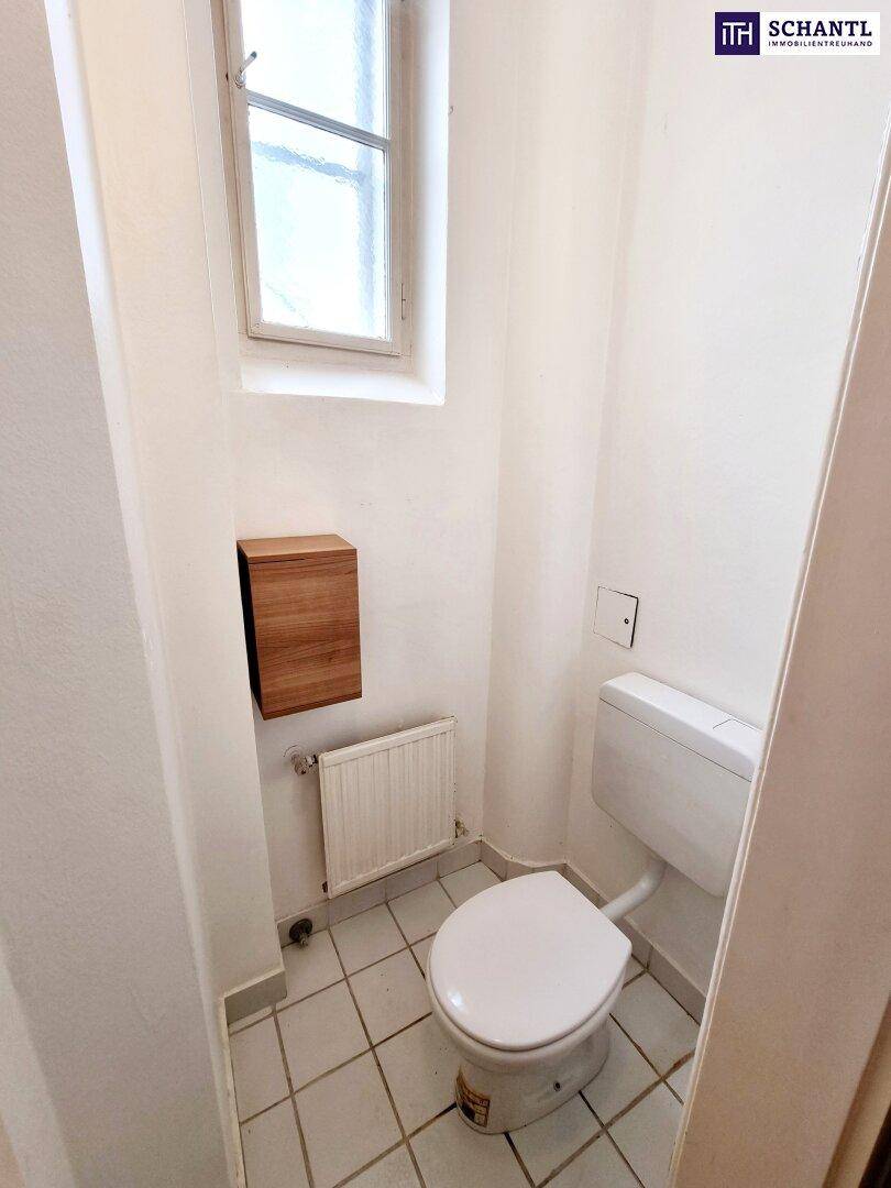 Kleines separates WC mit Toilette, Fenster und weiß gefliestem Boden.
