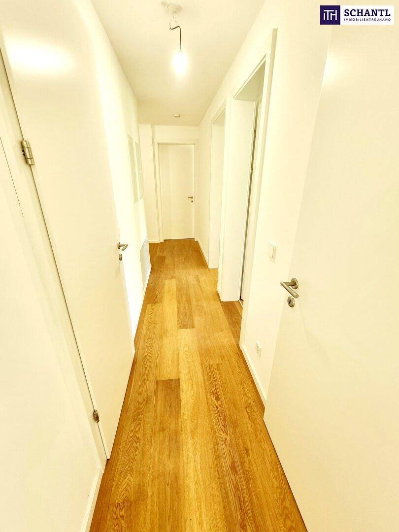 Langer, heller Flur mit Holzfußboden und mehreren weißen Türen zu angrenzenden Räumen.