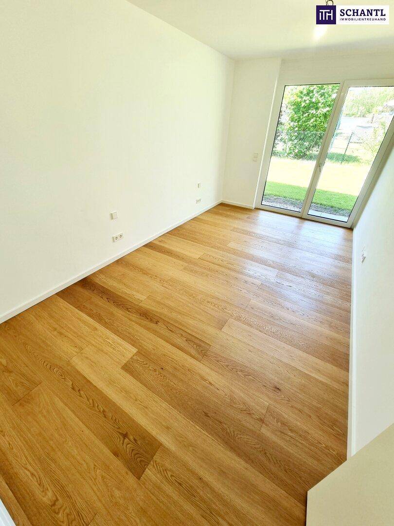 Geräumiges Zimmer mit Holzboden und großen Fenstern, die viel Tageslicht hereinlassen und Gartenblick bieten.