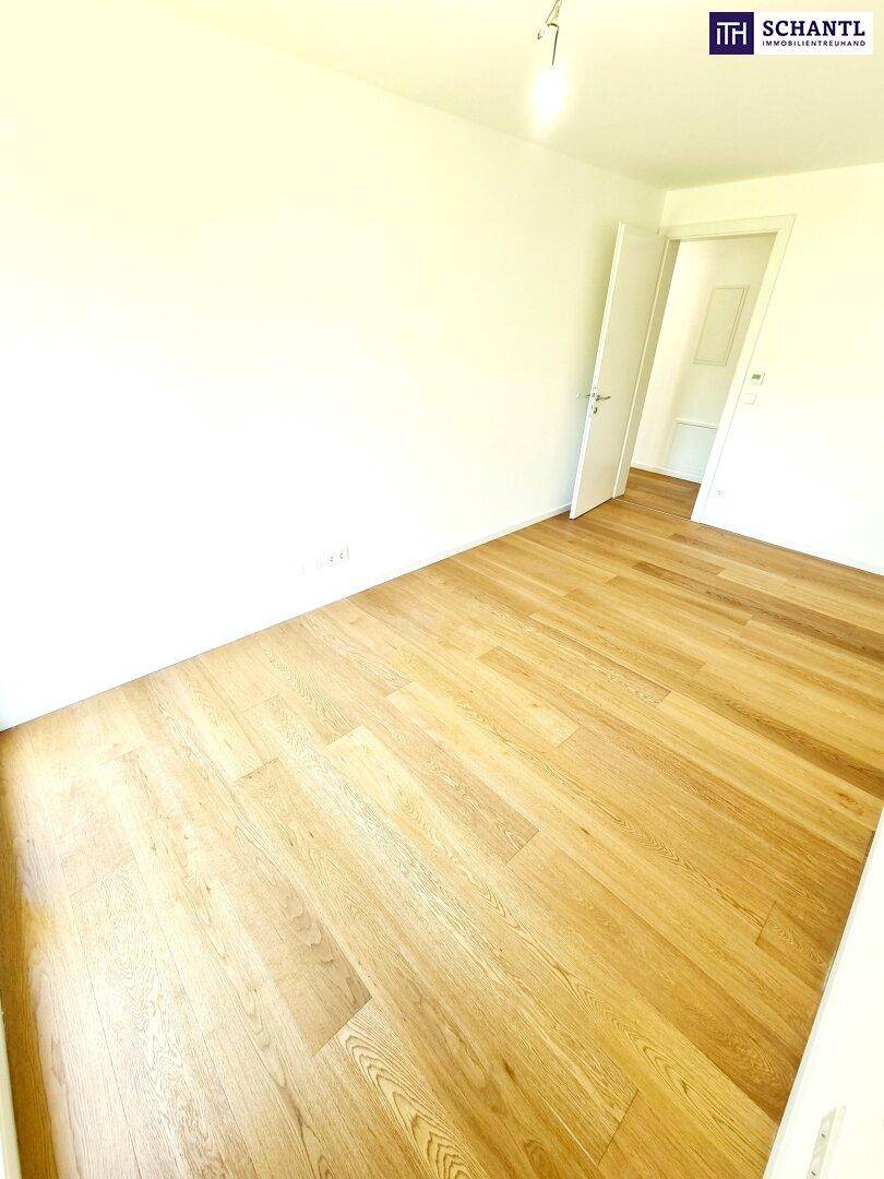 Leeres Schlafzimmer mit hellem Holzfußboden und weiß gestrichenen Wänden.