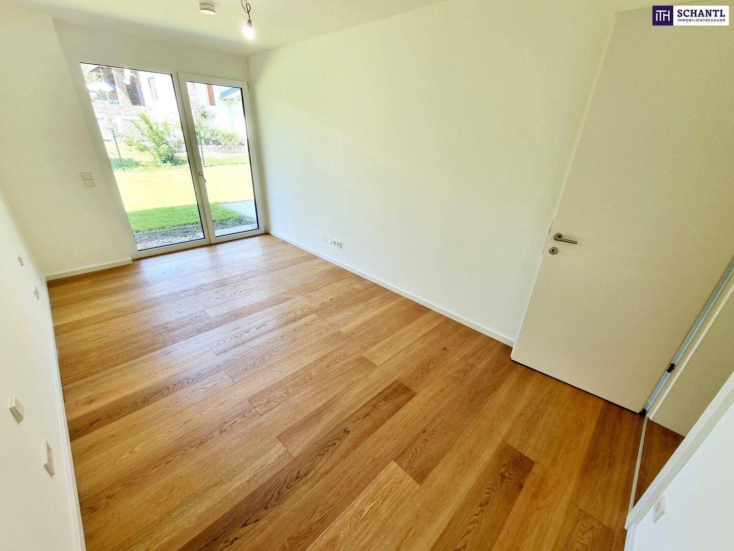Lichtdurchfluteter Raum mit Holzboden und direktem Zugang zum grünen Außenbereich.