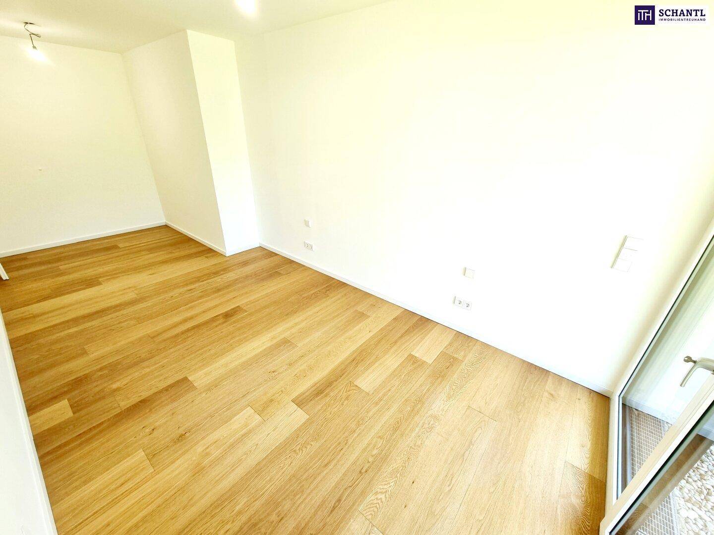 Geräumiges Schlafzimmer mit Holzboden und viel Tageslicht durch die große Terrassentür.