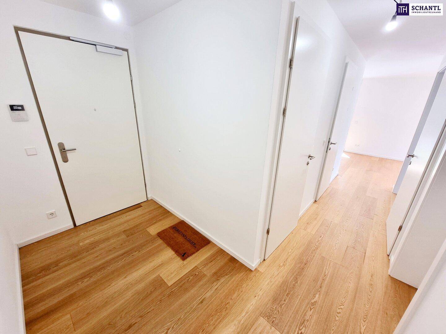 Heller Flur mit Holzboden und mehreren weißen Türen, die zu den Zimmern führen.