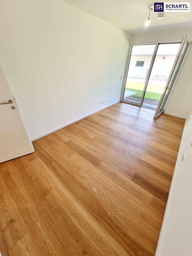 Helles Zimmer mit Holzboden und einer weit geöffneten Glastür zum Außenbereich.