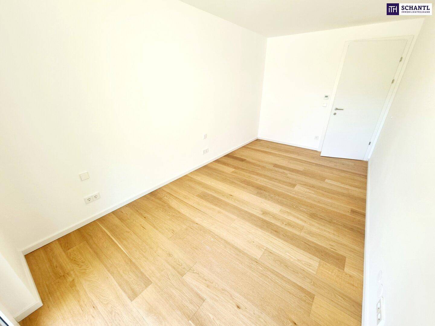 Leeres, helles Zimmer mit Holzboden und einer weißen Tür, bereit zur individuellen Gestaltung.