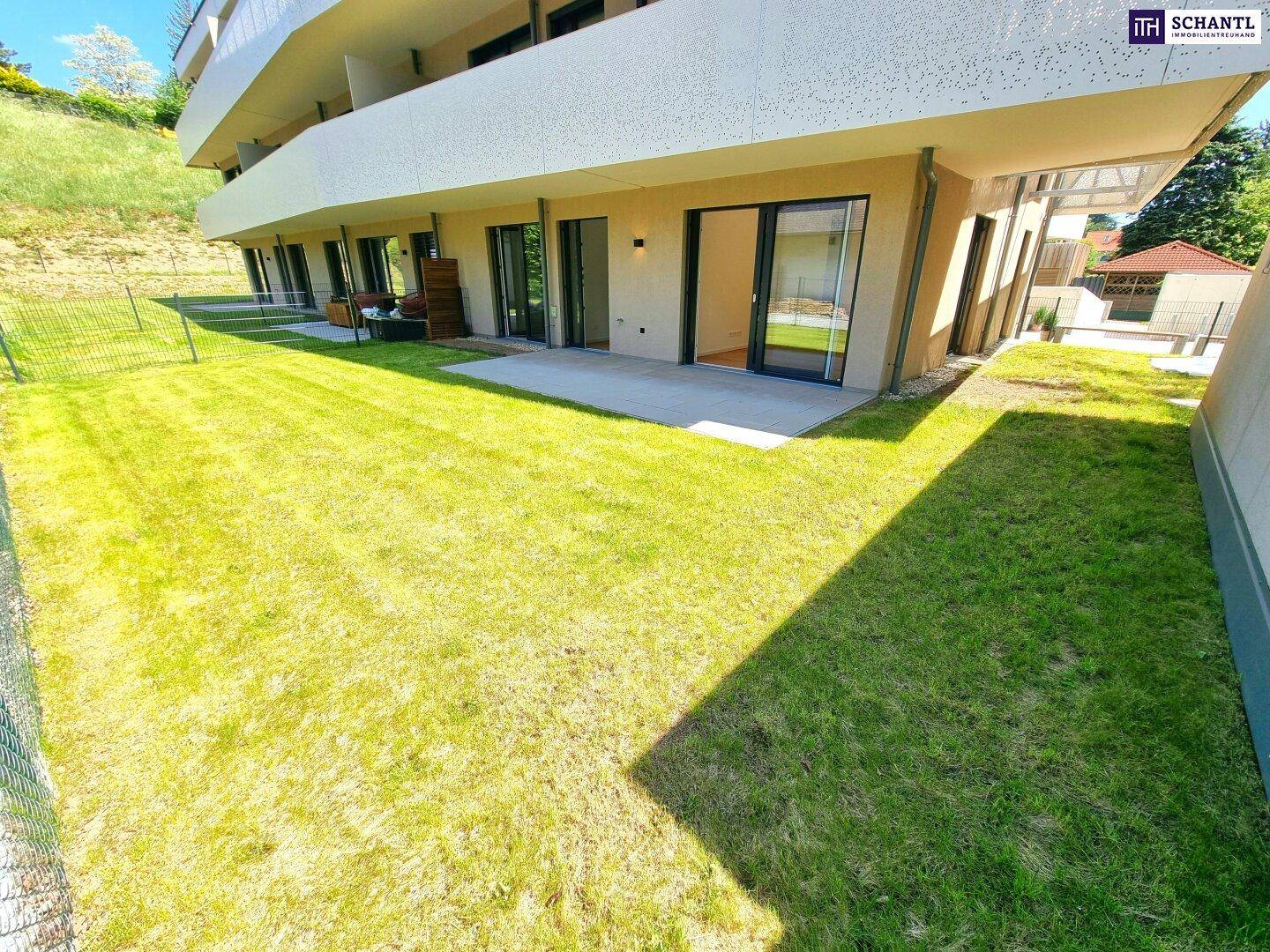 Moderner Neubau mit großem Rasenbereich und privater Terrasse im Erdgeschoss, umgeben von Grün.