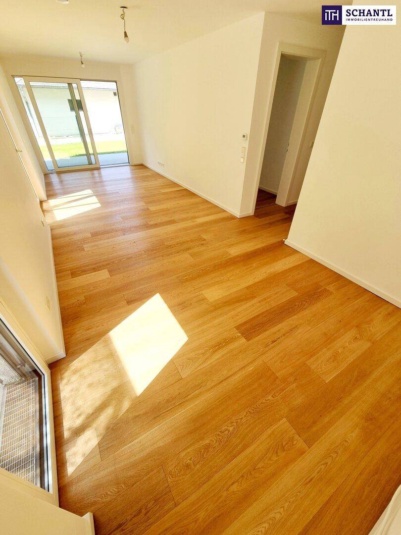 Lichtdurchfluteter Raum mit hellem Holzboden und Zugang zu einem Außenbereich.