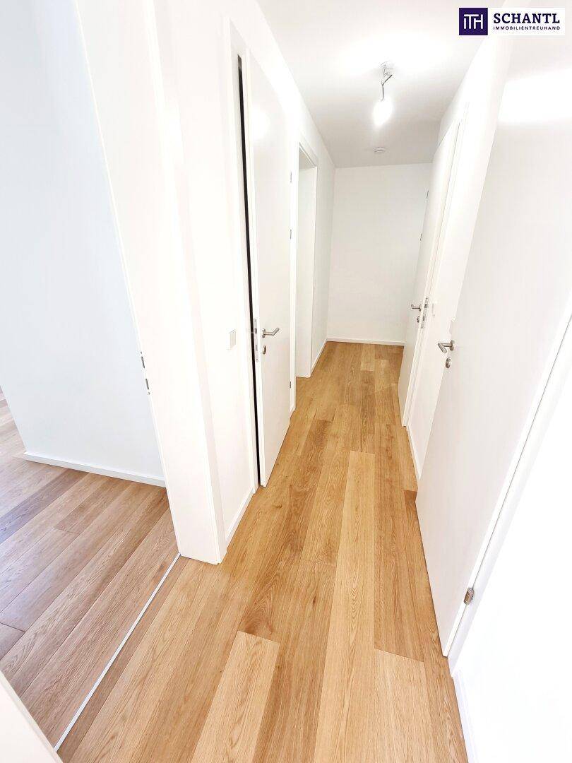 Heller Flur mit modernem Holzfußboden und weißen Türen, der zu verschiedenen Räumen führt.
