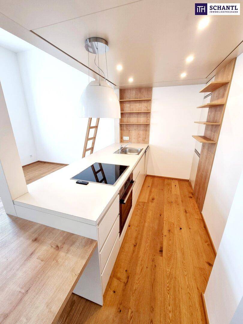 Moderne Küchenzeile mit Induktionskochfeld, Backofen und Holzregalen in einem hellen Raum.